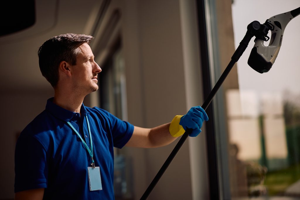 A professional commercial window cleaning services provider cleans a glass pane in an office.